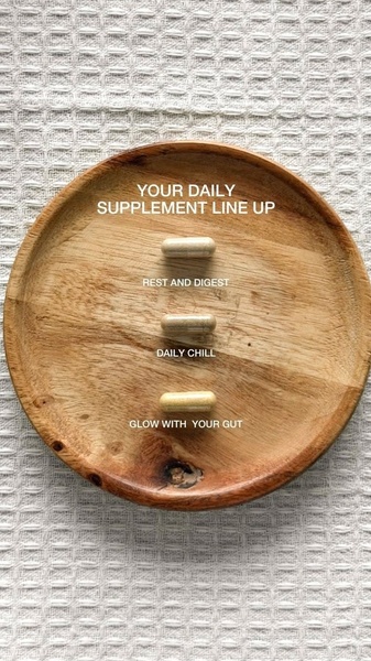 A clean, top-down view of three dietary supplement capsules arranged on a wooden plate, each labeled with a distinct daily benefit.